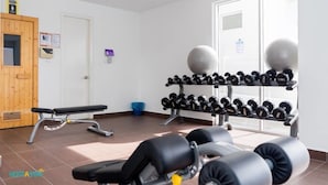 A gym with exercise equipment, a bench, and a rack of dumbbells. - Duet HomeStay (Seri Kembangan)