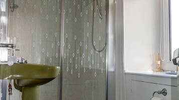 A bathroom with a shower, toilet, sink, and a window.