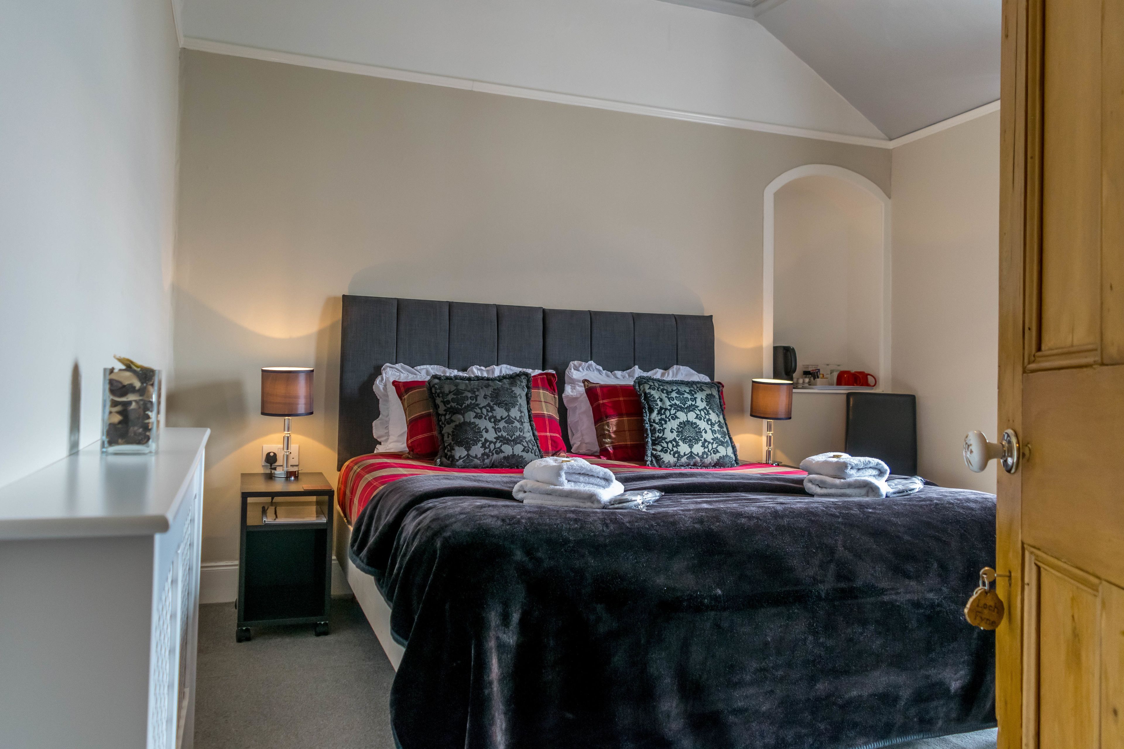 Un dormitorio ordenado con cama, lámparas de noche, mesitas de noche y una puerta de madera.