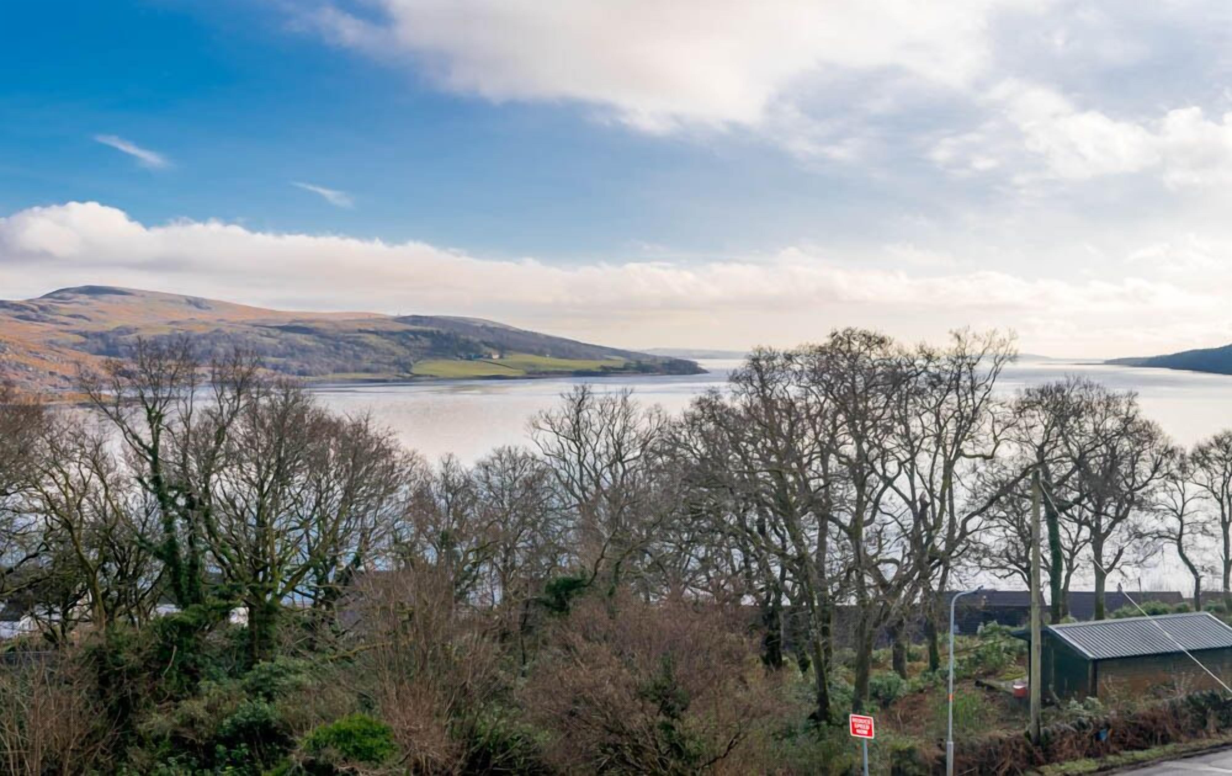 A scenic view of a lake surrounded by hills and trees.