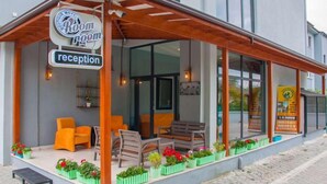 A boutique motel with a reception area, outdoor seating, and potted plants.