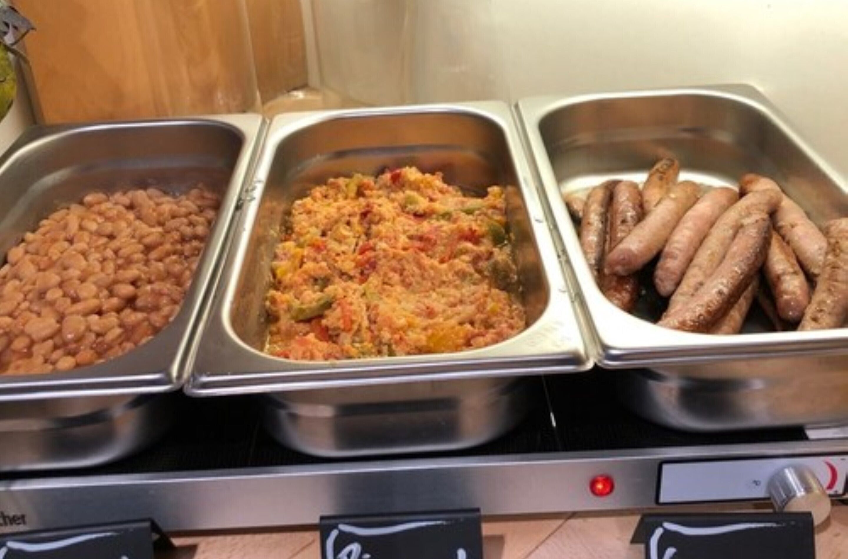A buffet with three food options: beans, a vegetable casserole, and sausages.