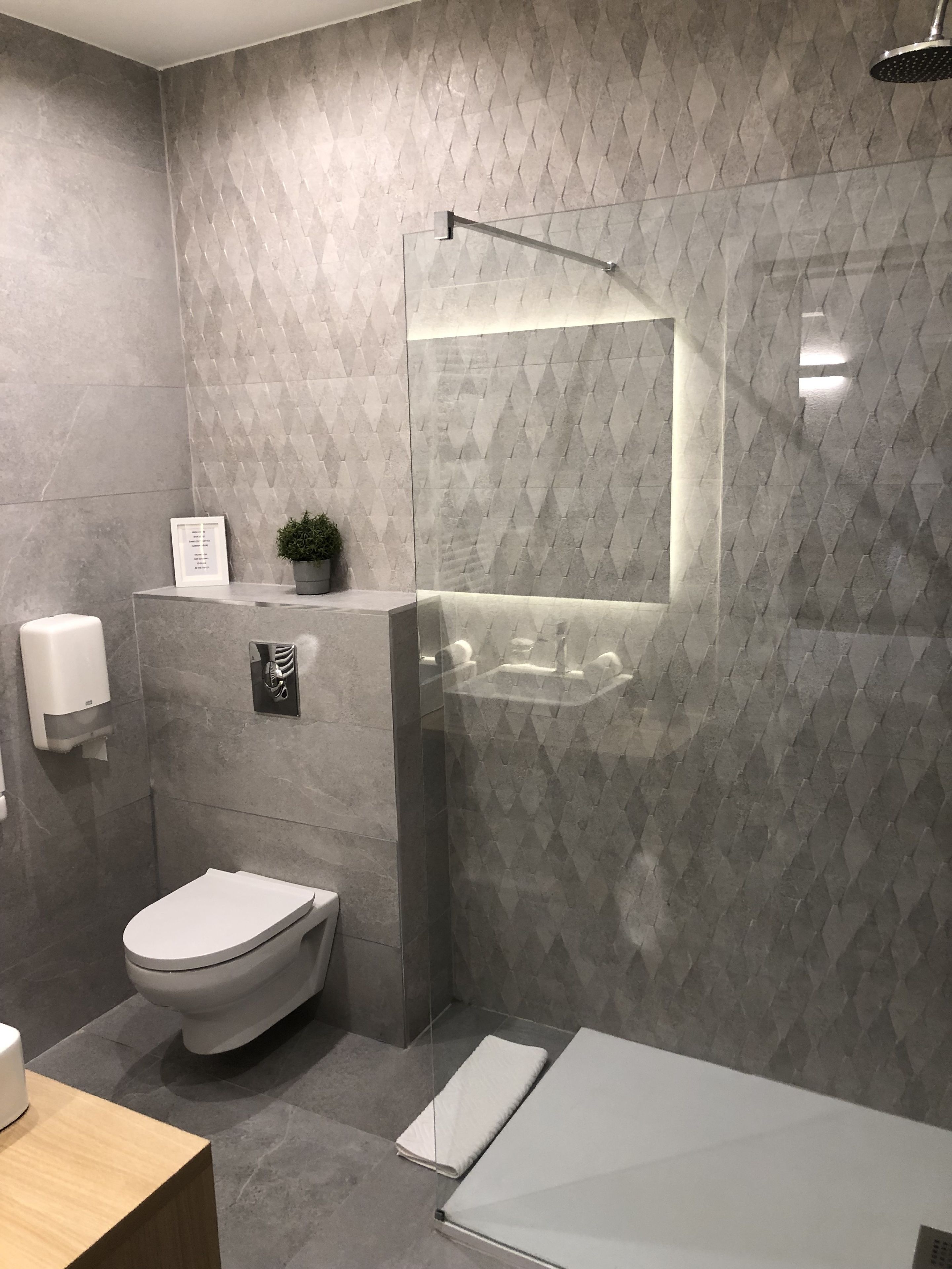 Un baño moderno con inodoro, lavamanos y zona de ducha.