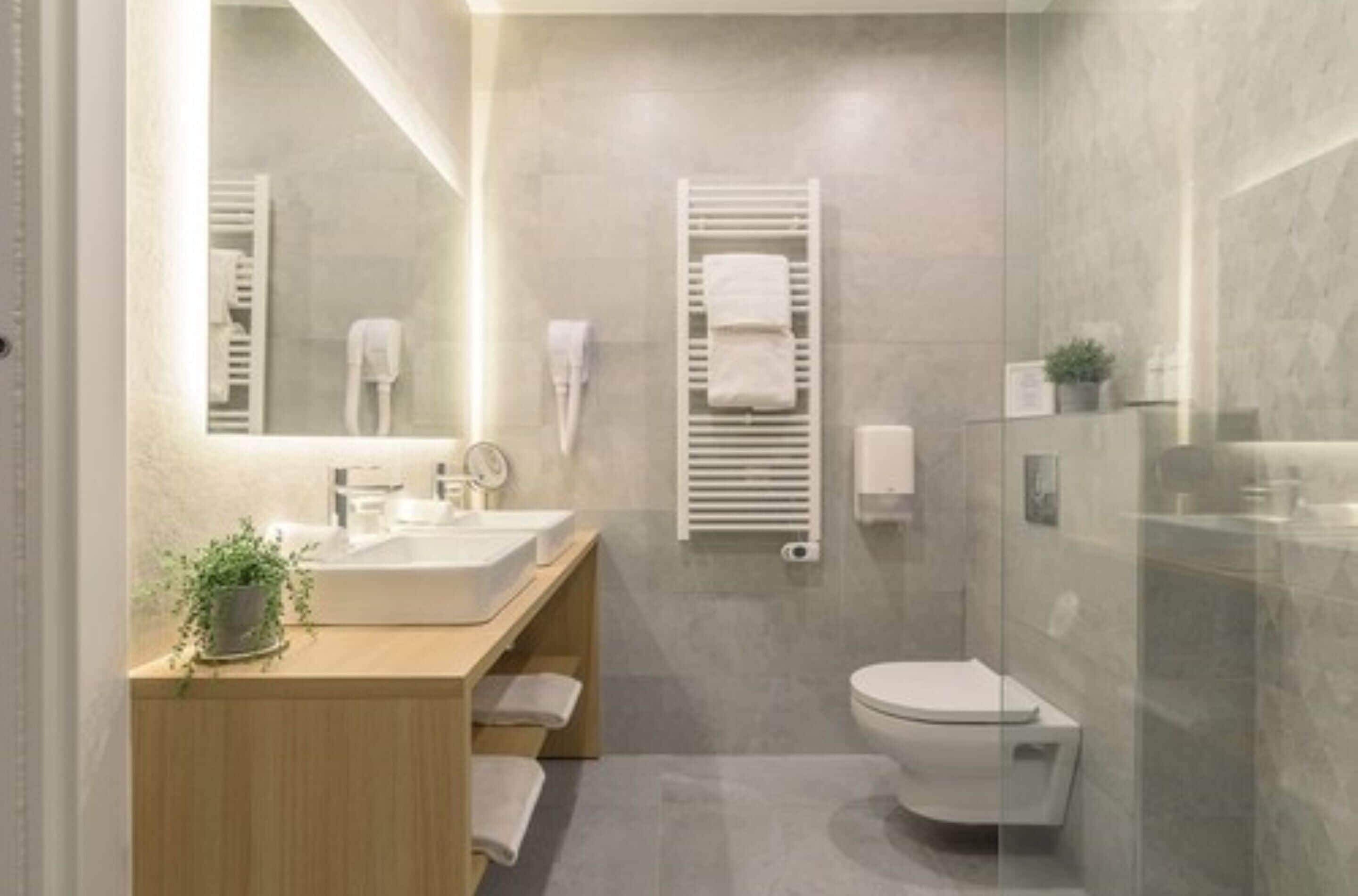 A modern bathroom with a large mirror, a sink, a toilet, and a glass shower enclosure.