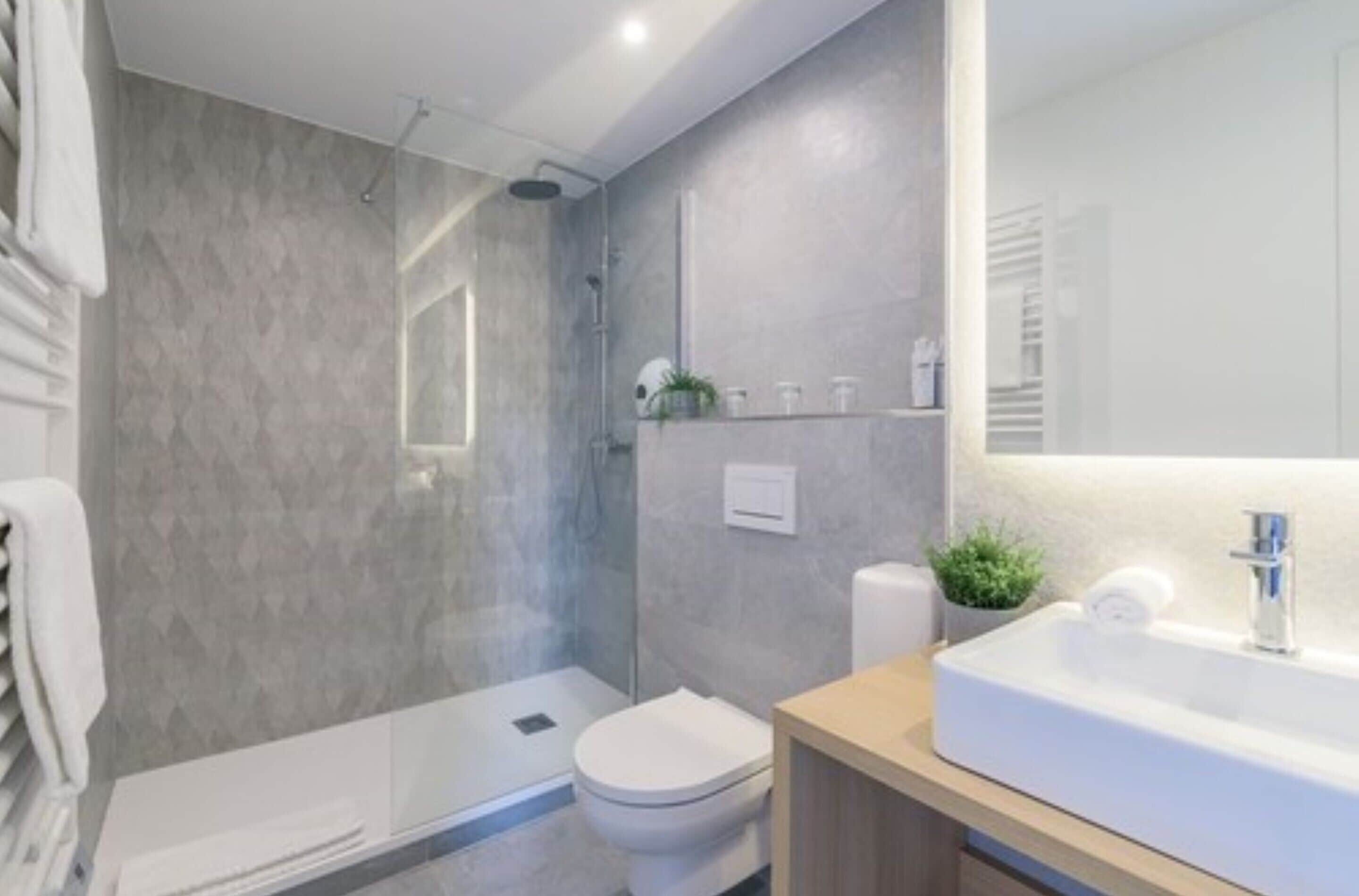A modern bathroom with a shower, toilet, and sink.