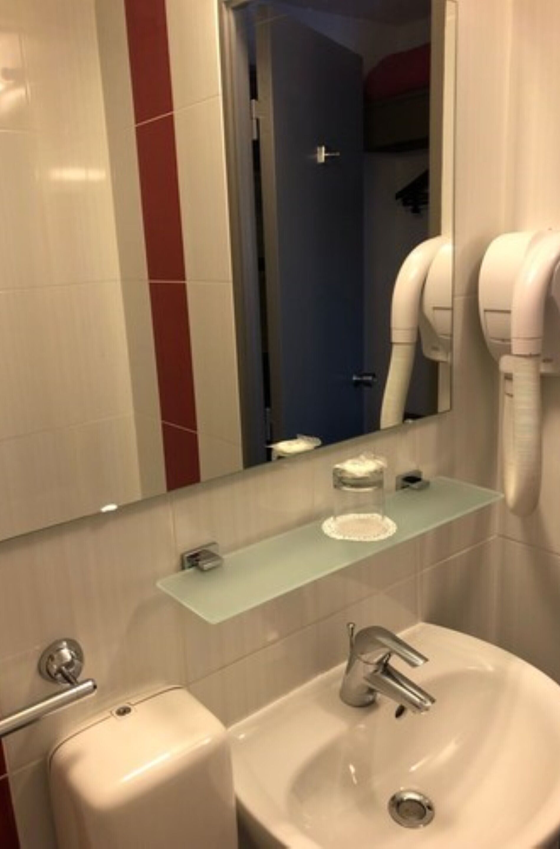 A bathroom with a sink, mirror, and hairdryer.