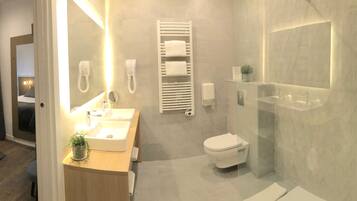 Una habitación de hotel moderna con una cama, un baño con ducha, lavamanos e inodoro.