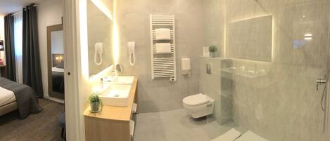 Et moderne hotelværelse med seng, badeværelse med bruser, vask og toilet.