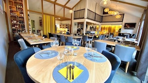 A restaurant with round tables, blue chairs, and a wooden interior. - Fasthôtel Biarritz Bidart Côte Basque - FH Collection (Bidart)