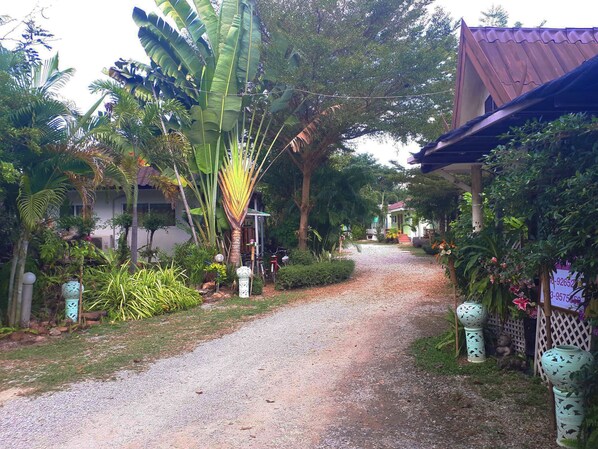 A gravel path leading through a lush garden with banana trees and various plants. - Leelawadee Resort (Sukhothai)