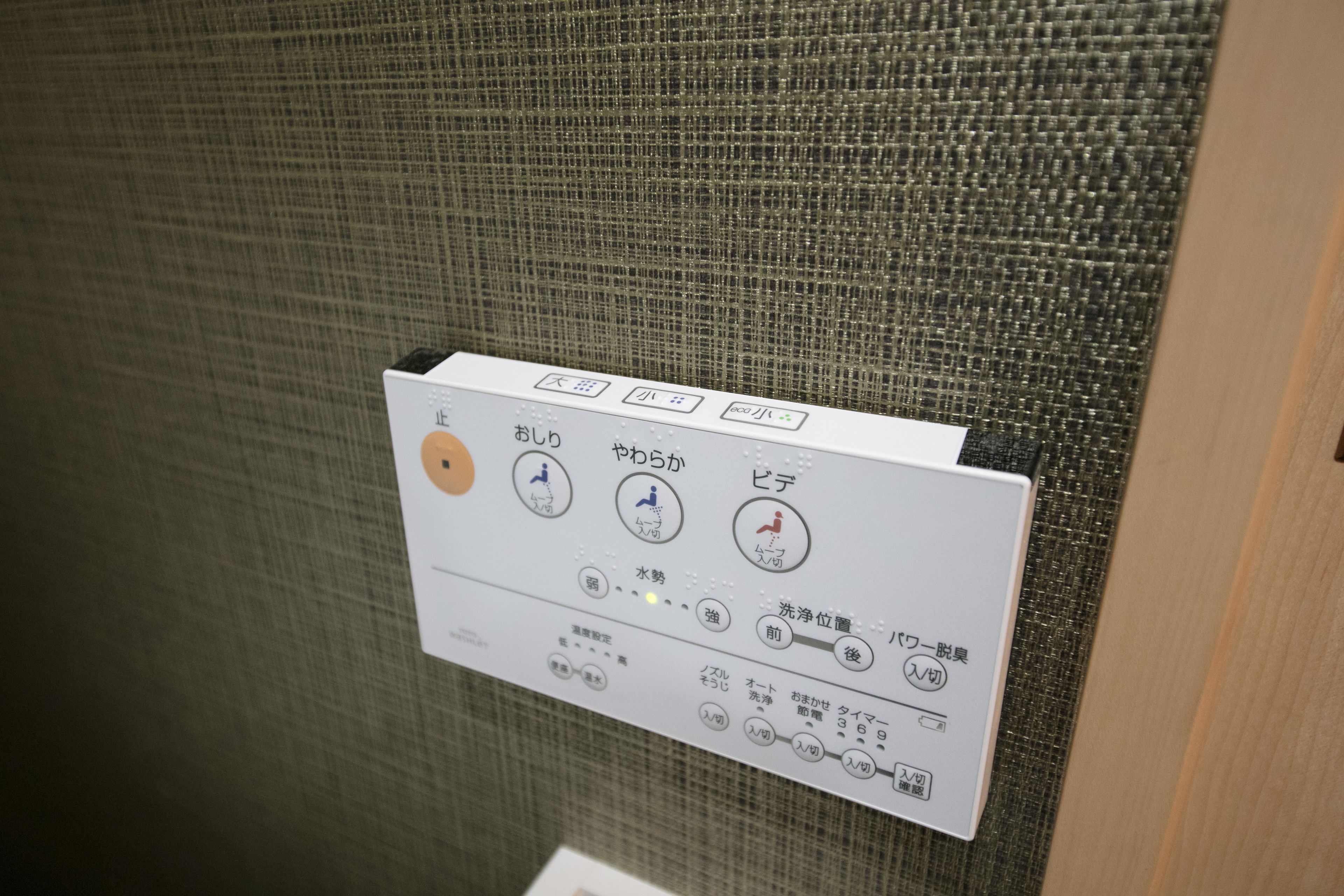 Ein Bedienfeld mit japanischen Anweisungen zur Steuerung einer Anlage, wahrscheinlich eine Toilette oder ein ähnlicher öffentlicher Raum.