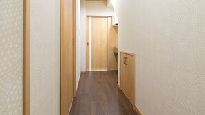 Un pasillo estrecho con suelo de madera y paredes con diseño, que lleva a una puerta al final.