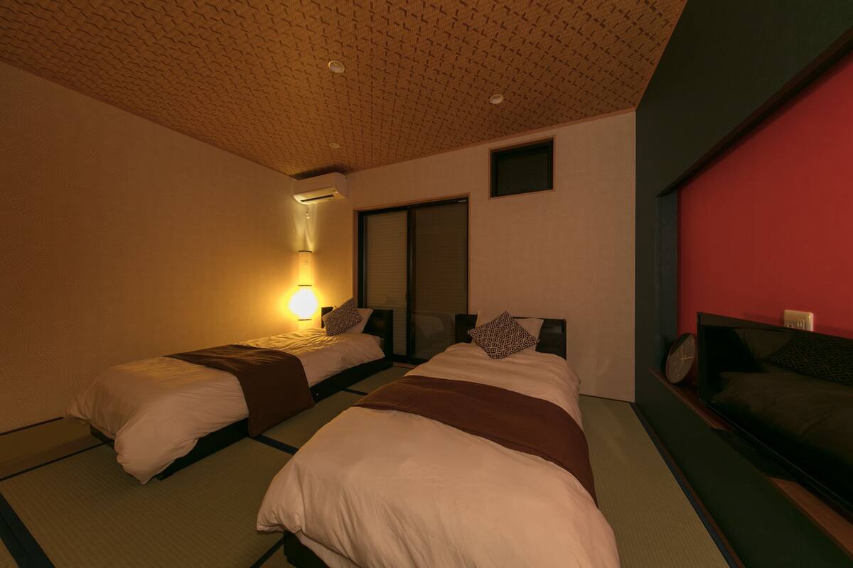 Une chambre d’hôtel avec deux lits, une télévision et un mur d’accent de couleur rouge.
