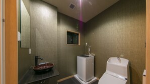 Un baño con lavamanos, inodoro y una ventana pequeña.