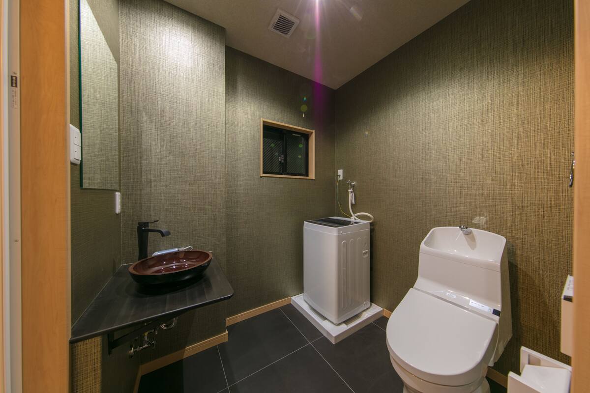 Une salle de bain avec un lavabo, des toilettes et une petite fenêtre.