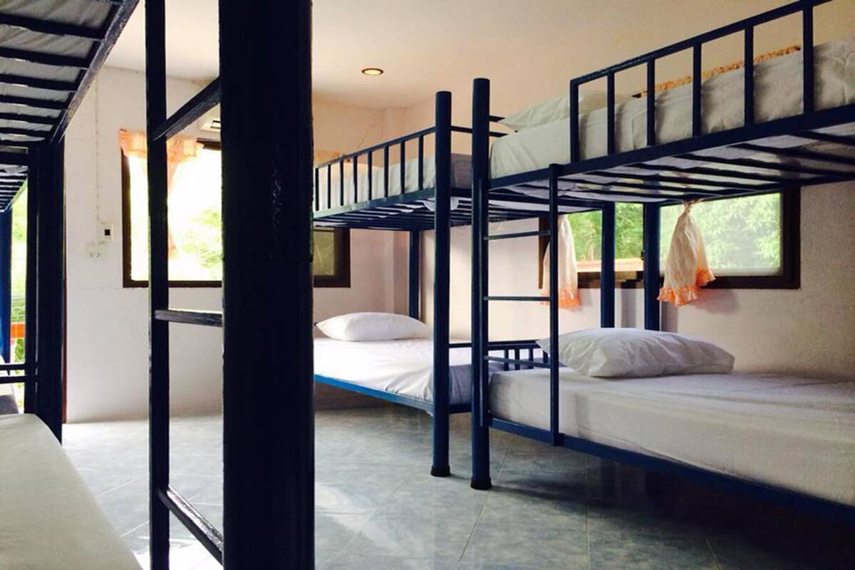 Habitación con literas, ventana, puerta y suelo de baldosas.