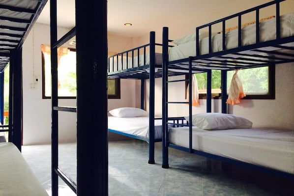 A bunk bed room with a window, a door, and a tiled floor.