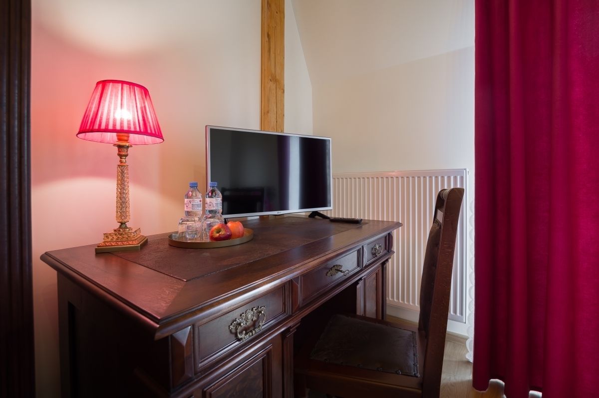 Ein Holztisch mit einem Fernseher, einer roten Lampe und einer Wasserflasche.