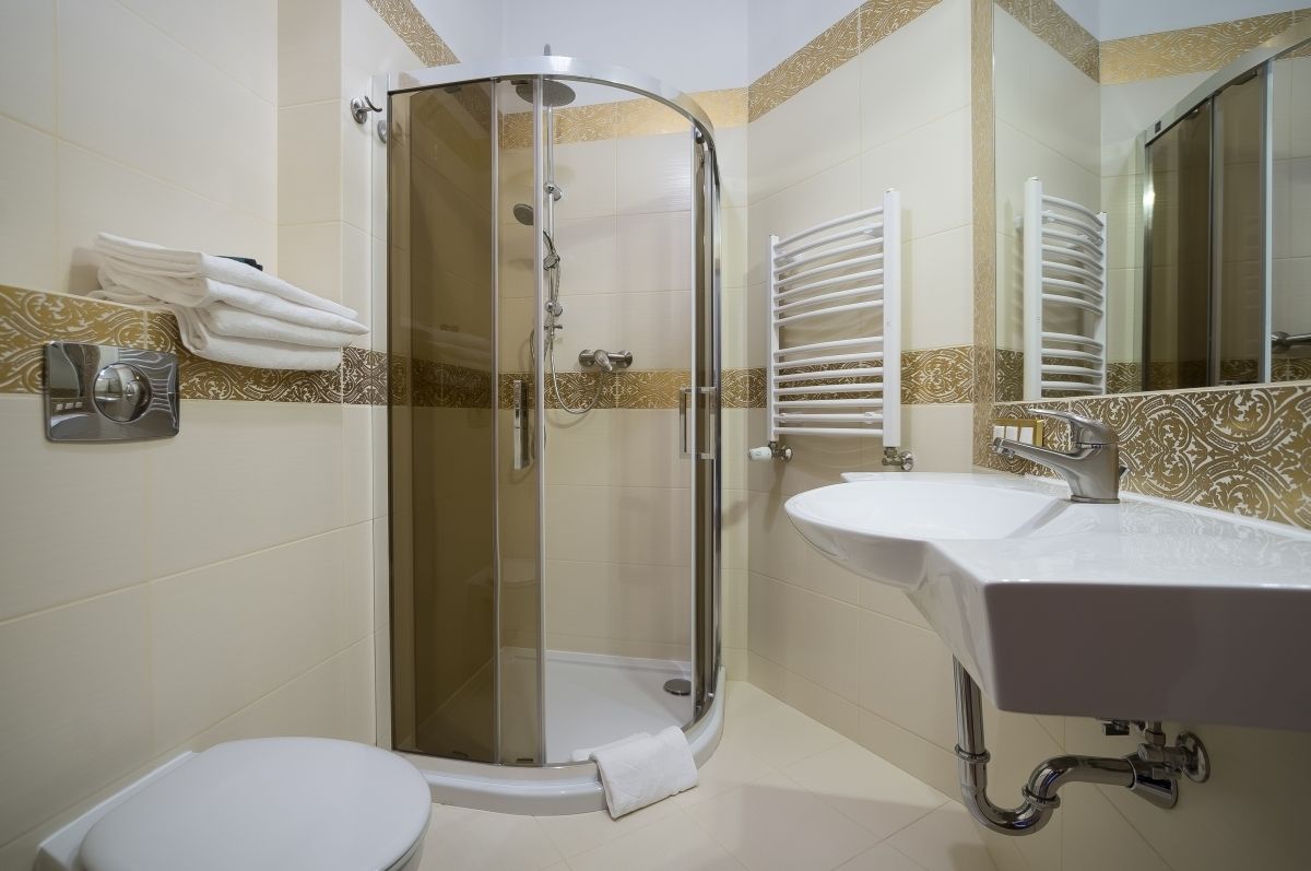 A modern bathroom with a glass-enclosed shower, a white sink, and a toilet.