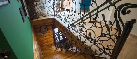 A wooden staircase with ornate metal railings, a green wall, and a blue chair in the background.
