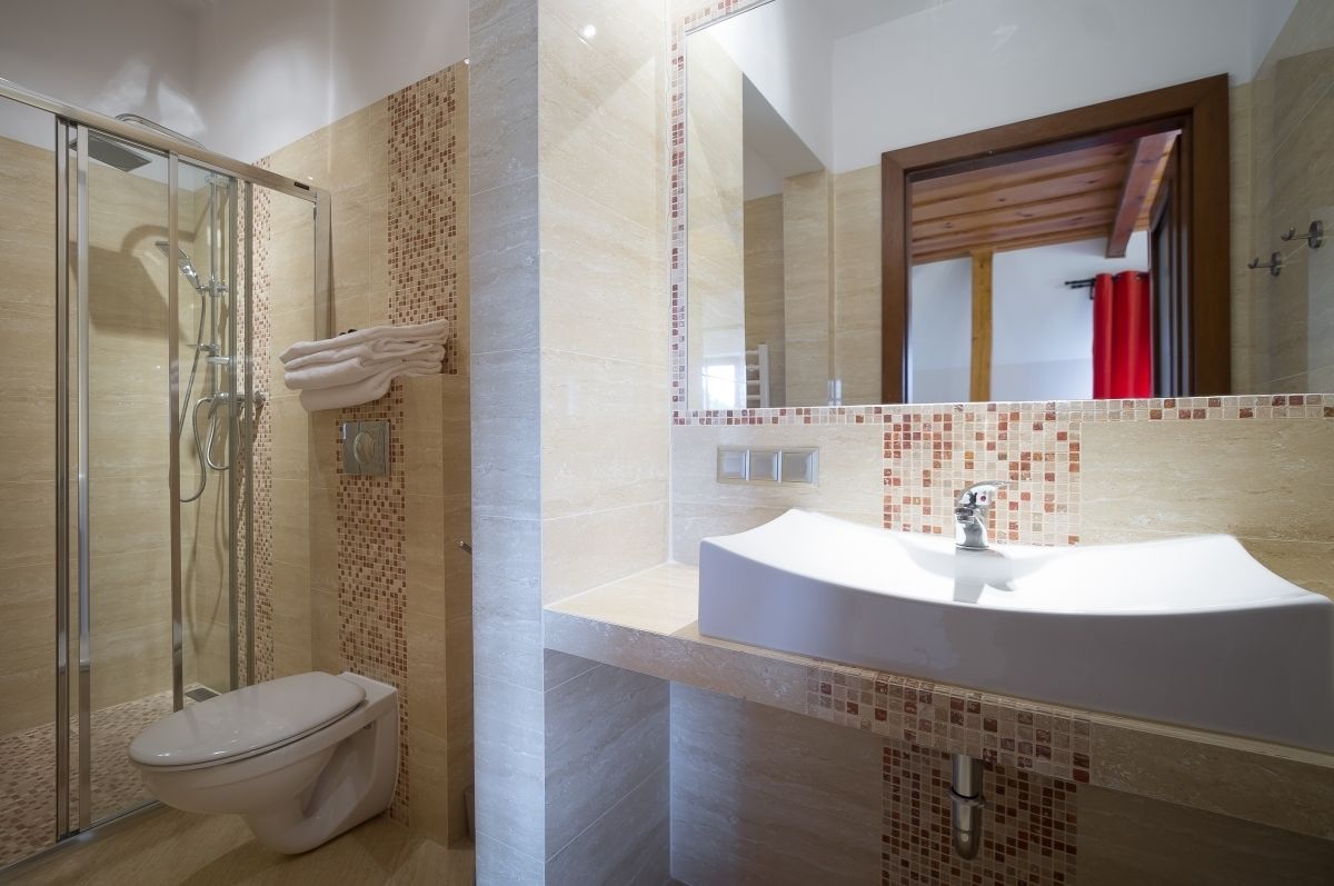 A modern bathroom with a glass-enclosed shower, a white toilet, and a sink with a tiled backsplash.
