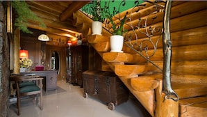 Un intérieur en bois avec un escalier en colimaçon, un coin repas avec une table et des chaises, et une plante suspendue.