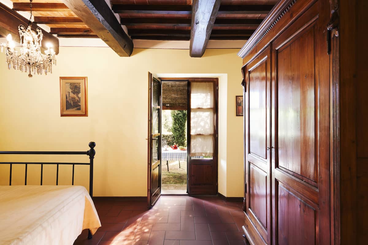 Un dormitorio con cama, armario de madera y candelabro.