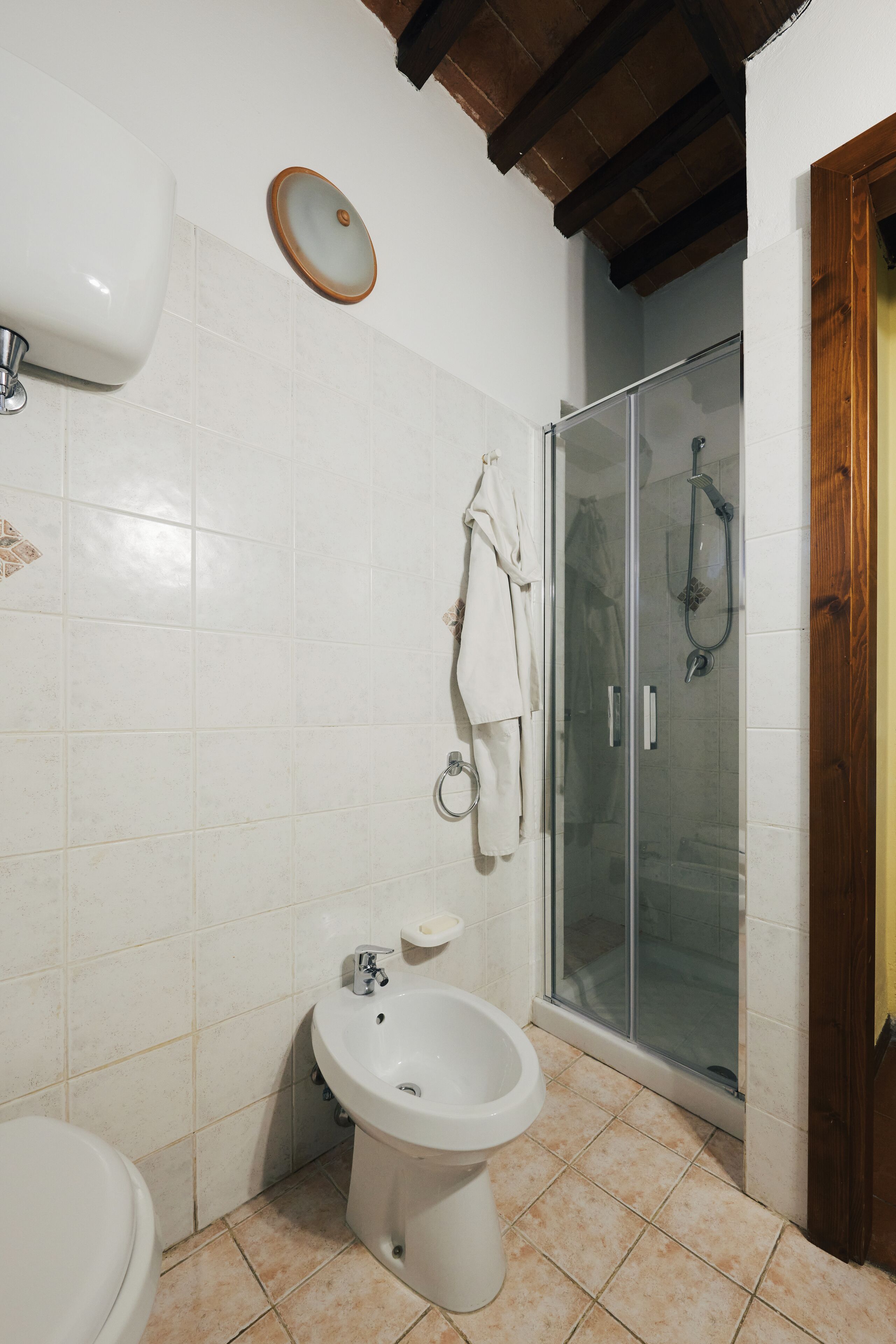 A bathroom with a toilet, bidet, and glass-enclosed shower.