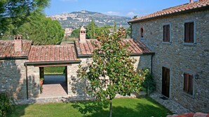 Un bâtiment en pierre avec un toit en tuiles, une petite tour et une vue sur une ville lointaine.