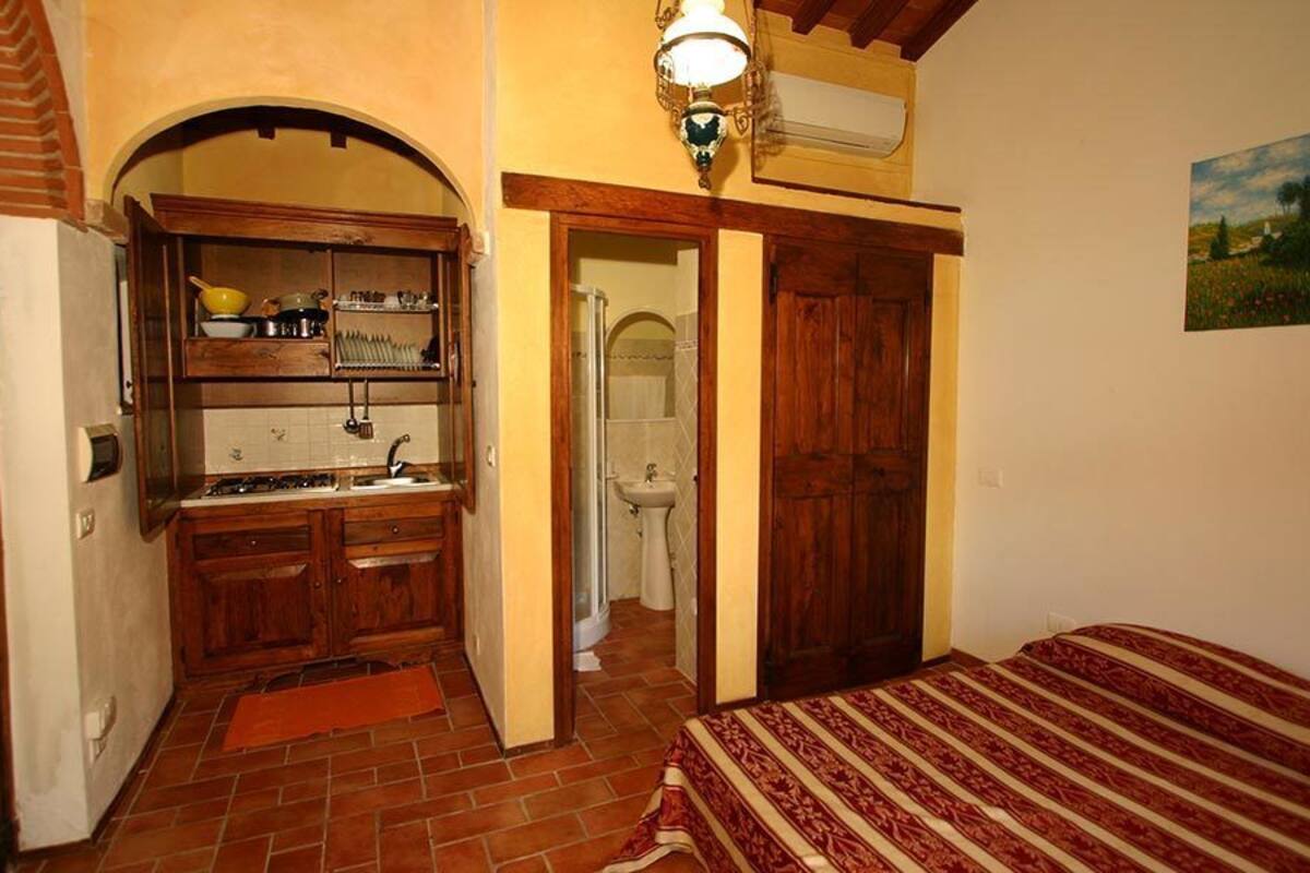 Habitación pequeña con cocina, baño y cama.