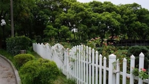 A white picket fence with lush greenery and trees in the background. - Grand Inn Xijiao State Guest Hotel (Shanghai)