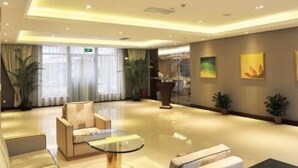 A modern hotel lobby with a glass coffee table, sofas, and potted plants. - Grand Inn Xijiao State Guest Hotel (Shanghai)