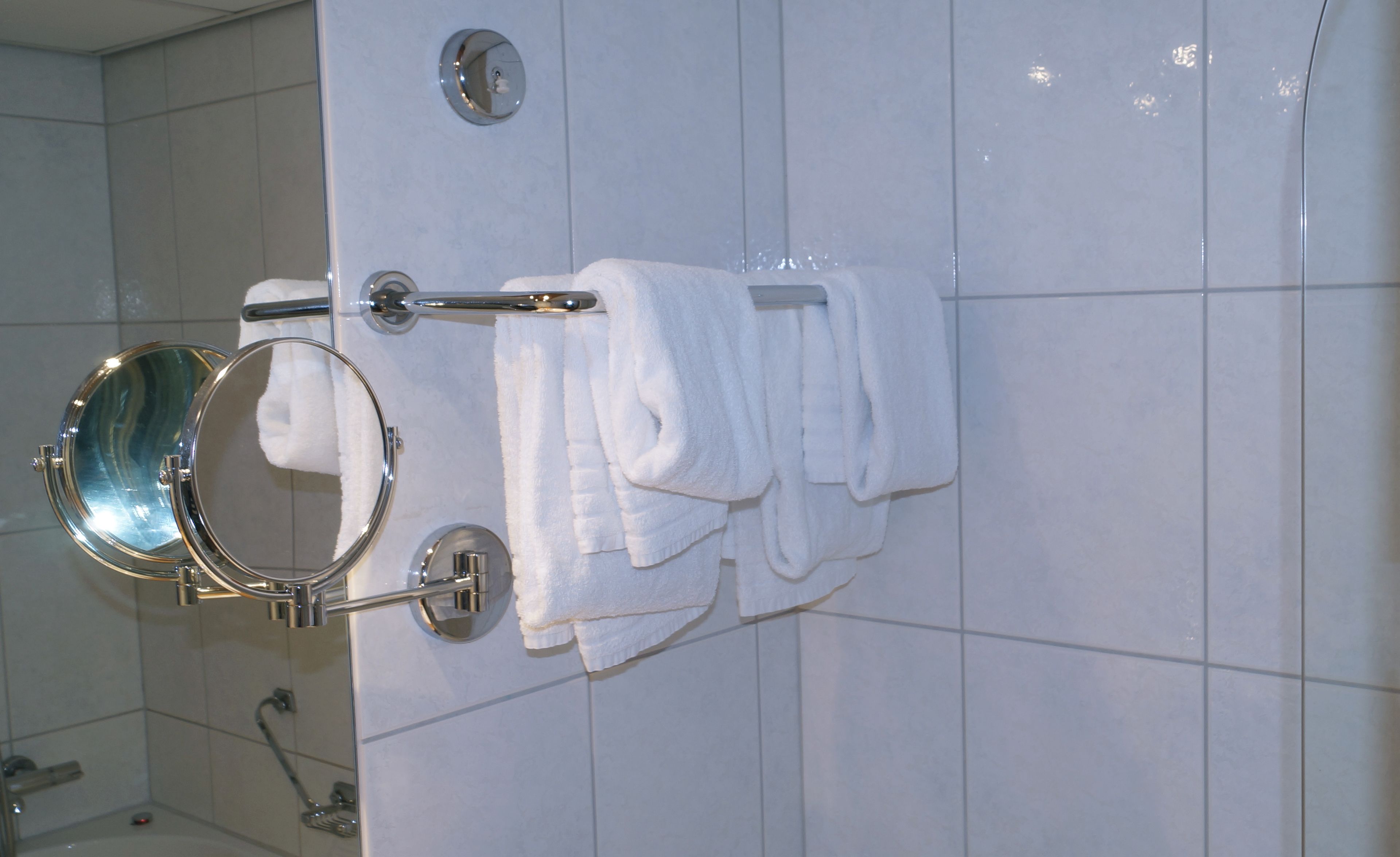 A bathroom with a mirror, towel rack, and a shower.