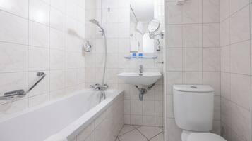 A modern bathroom with a bathtub, sink, toilet, and a mirror.