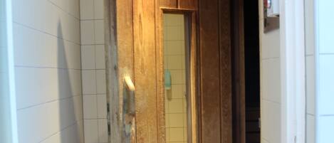 A hallway with a wooden door and a mirror.