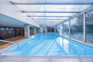 Una piscina techada, sillones reclinables de piscina