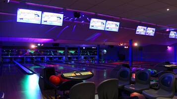 Uma pista de boliche com várias pistas, luzes neon e diversas bolas de boliche.