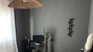 Ein Schlafzimmer mit Bett, Nachttisch, Lampe und einem an der Wand befestigten Fernseher.