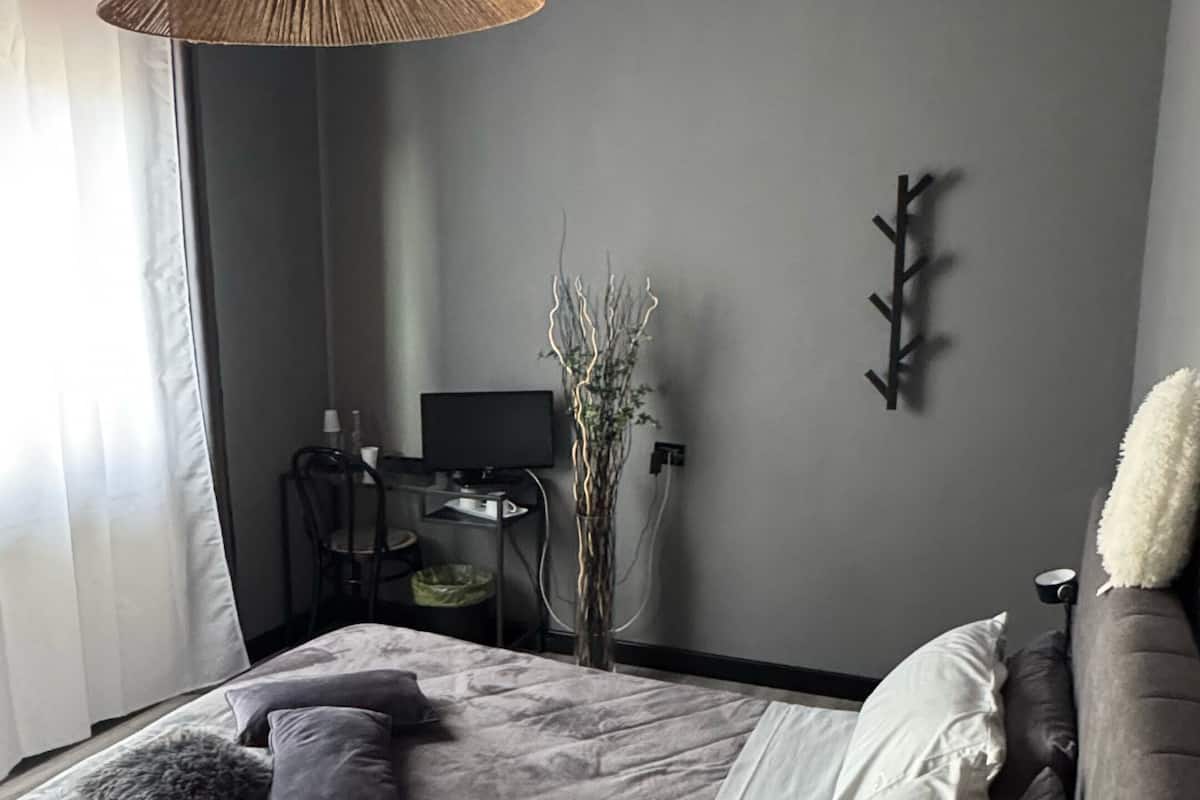 Une chambre à coucher comprenant un lit, une table de chevet, une lampe et un téléviseur fixé au mur.
