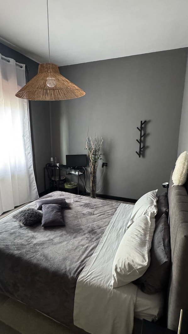Une chambre à coucher comprenant un lit, une table de chevet, une lampe et un téléviseur fixé au mur.