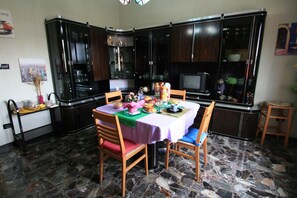 A dining area with a table set for four, surrounded by dark wooden cabinets. - B&B Frontepista (Pescara)