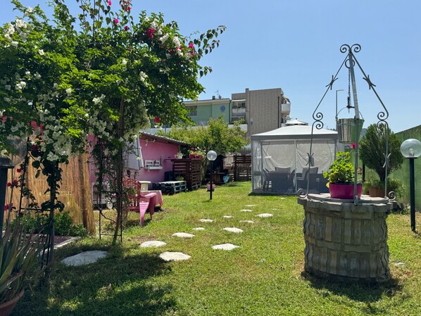 A garden with a gazebo, stepping stones, and potted plants. - B&B Frontepista (Pescara)