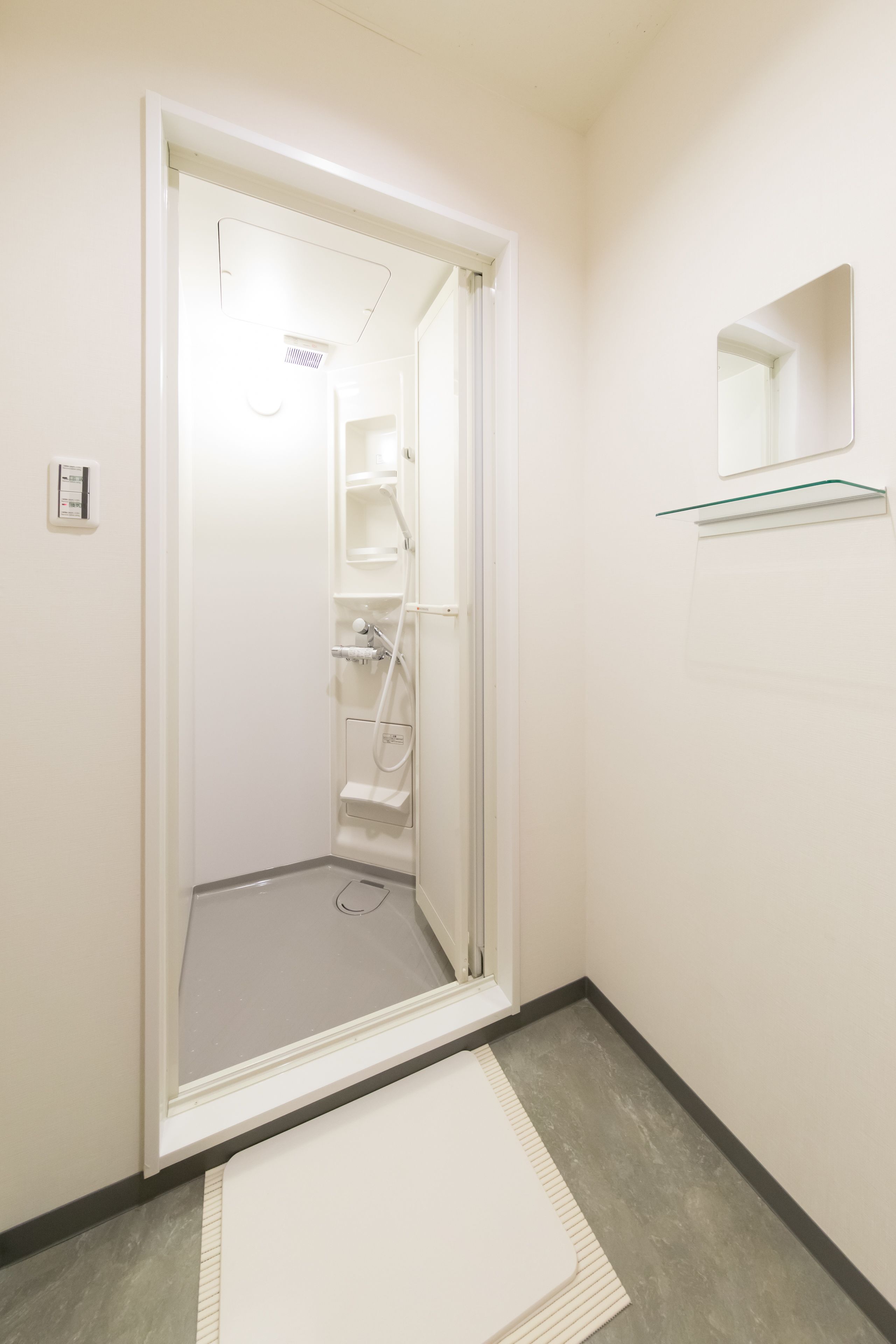 Une salle de bain avec une douche, une étagère en verre et un miroir.