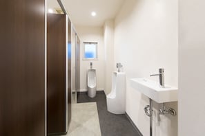 A modern bathroom with a urinal, a sink, and a window. - Rota Hostel (Osaka)