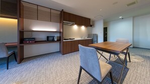 A modern kitchen with built-in appliances, a dining area with a wooden table and chairs, and a carpeted floor. - Rota Hostel (Osaka)