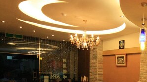 A restaurant interior with a modern chandelier, brick wall, and glass partition. - Ri Yue Hu Pan Hotel (Yuchi)