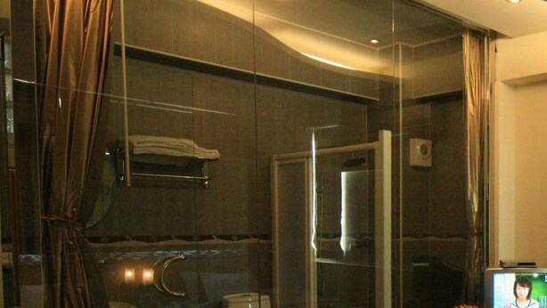 A modern bathroom with a glass shower enclosure, a towel rack, and a visible toilet. - Ri Yue Hu Pan Hotel (Yuchi)