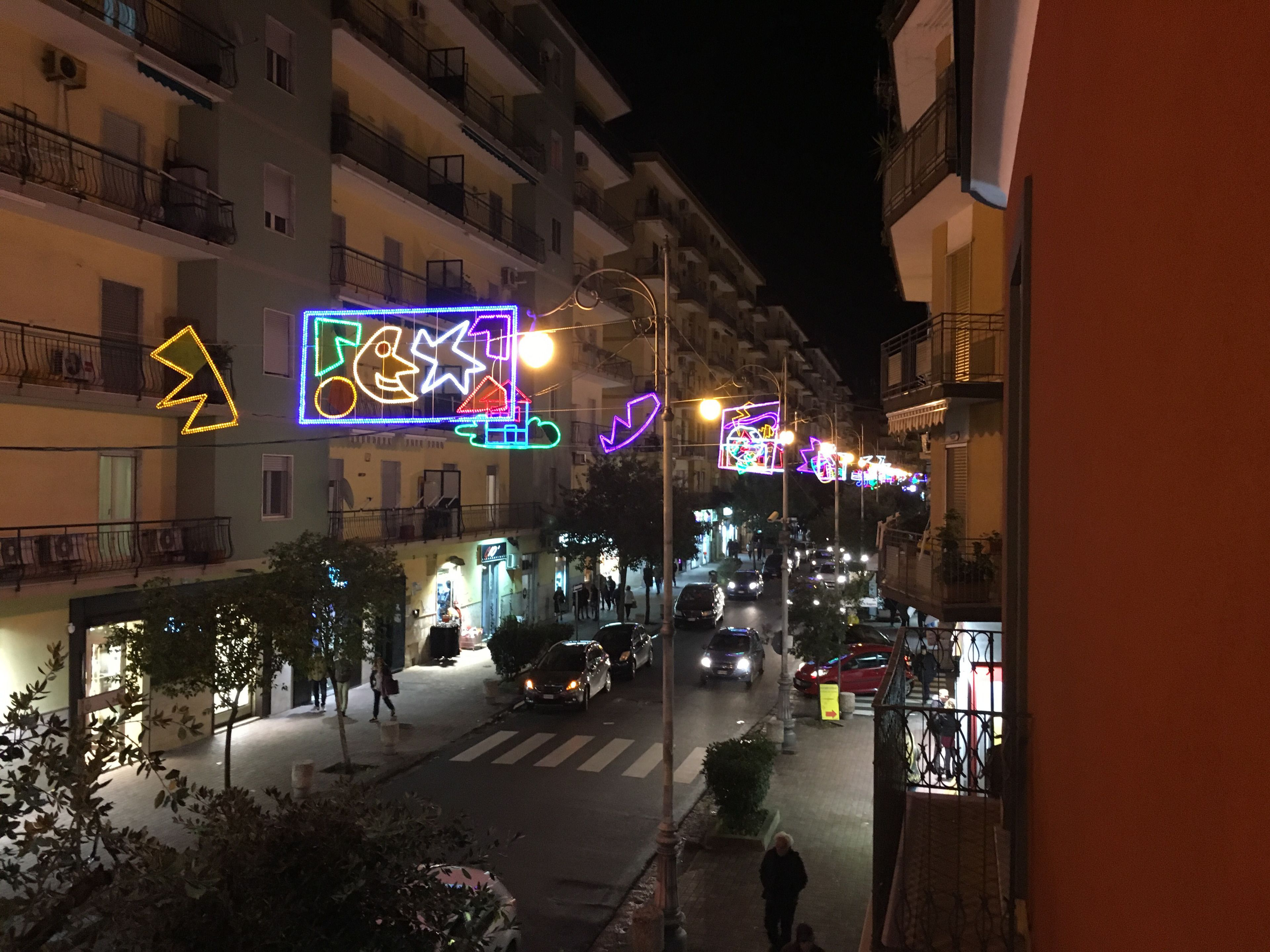 Une rue de nuit, illuminée par des enseignes au néon, des bâtiments et des voitures.