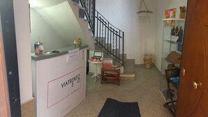 A reception area with a staircase, a reception desk, a small table with a basket, and a shelf with bags. - B&b Viatrento30 (Salerno)