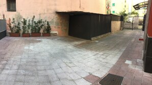 A paved courtyard with potted plants, a black gate, and a building with peeling paint. - B&b Viatrento30 (Salerno)